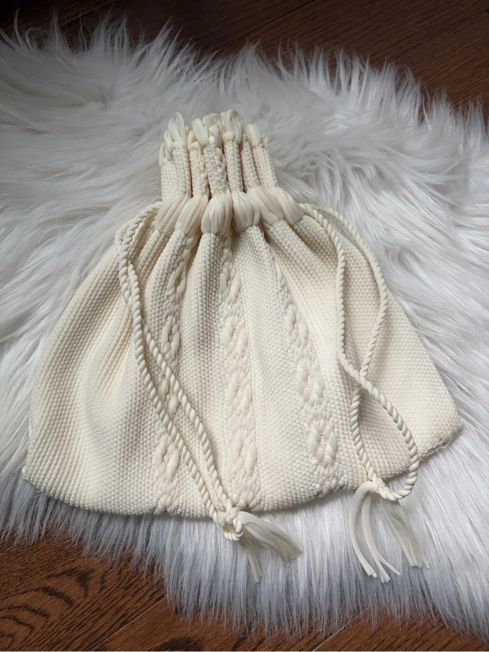 Cream cable knit drawstring bag with braided rope details